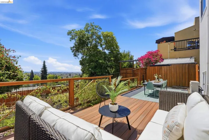 Expansive composite deck featuring a cable railing system, wood-finish privacy fence, and a lower patio area