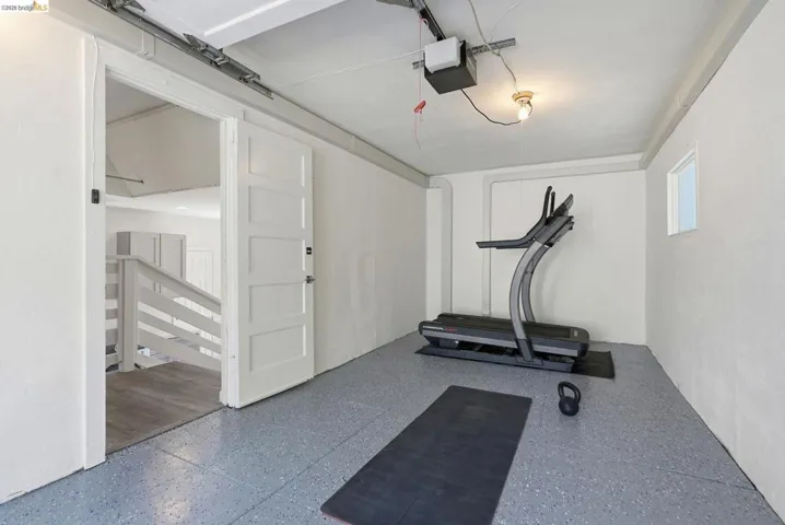 Finished garage space featuring speckled epoxy flooring, white painted walls, and a small window