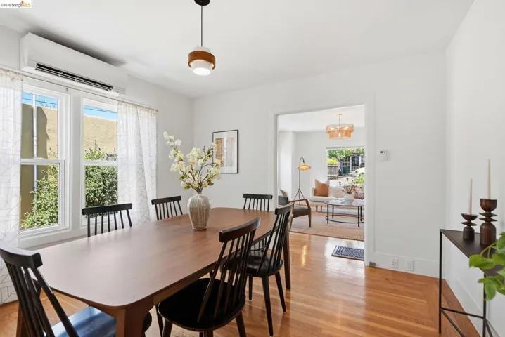 Dining area with a single-light pendant fixture, wood-finish flooring, and a wide cased opening to an additional living space