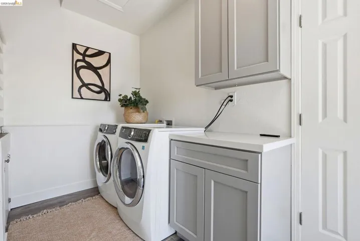 Dedicated laundry area featuring light gray cabinetry, a white countertop, and wood-finish flooring