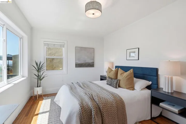 Bedroom featuring abundant natural light, wood-finish flooring, white walls, and a modern drum light fixture