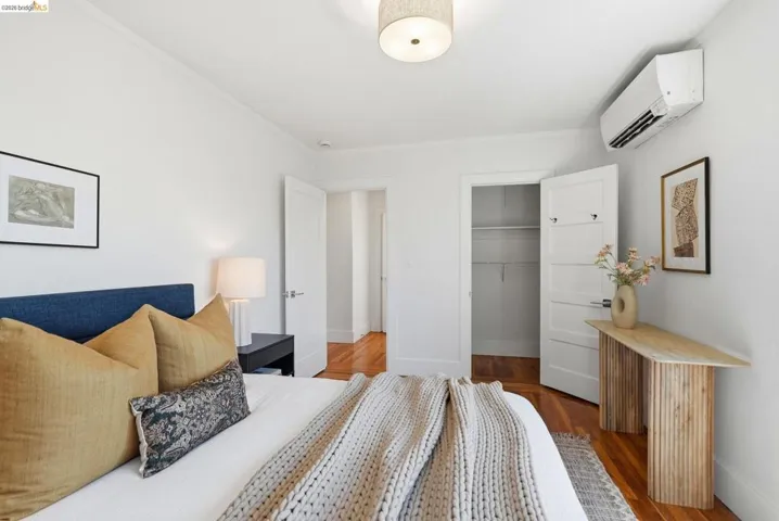 Bedroom featuring hardwood flooring, white walls, and a ceiling-mounted light fixture