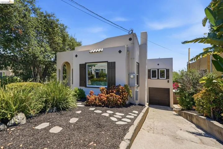 Stucco exterior featuring dark shutters, an arched entry, and a prominent front window