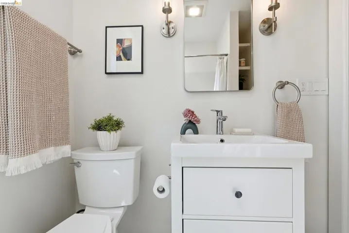 Bathroom featuring a white vanity with integrated sink, brushed nickel fixtures, a framed mirror, and wall sconces