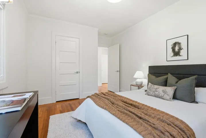 Bedroom featuring wood-finish flooring, white trim, and a window with natural light