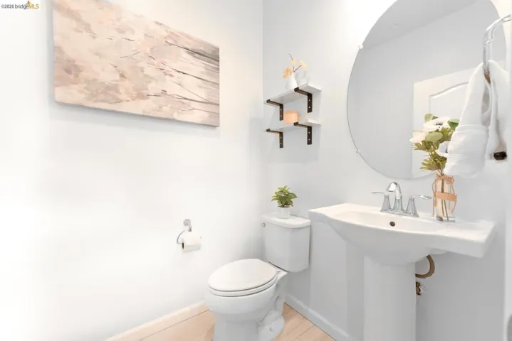 Pedestal sink with chrome faucet, complemented by a round wall-mounted mirror
