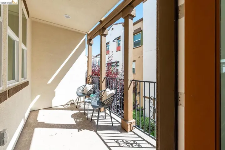 Outdoor balcony featuring a concrete floor, stucco exterior, and a decorative metal railing