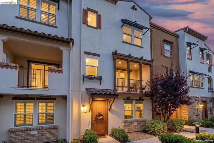 Stucco exterior featuring a tiled entry overhang and an open balcony with wood-look beams. *digitally enhanced