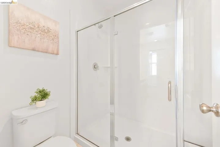 Shower enclosure with clear glass door and brushed nickel hardware, featuring a white tile surround and recessed shelving