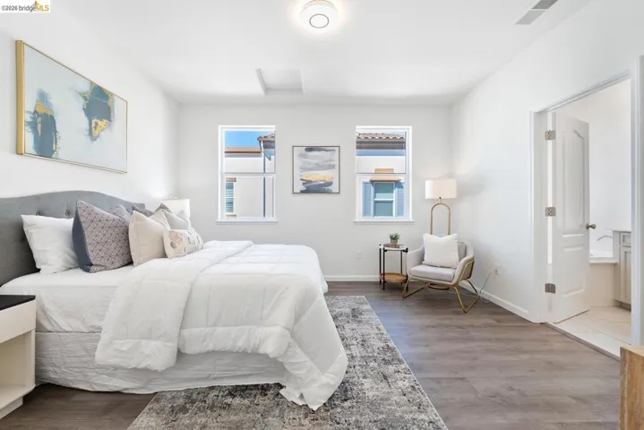 Spacious room featuring wood-finish flooring, two windows with white frames, and a recessed ceiling element
