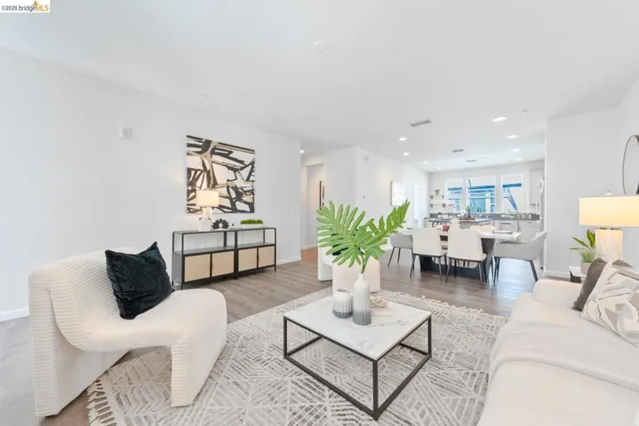 Open-concept living area with wood-finish flooring, recessed lighting, and white walls