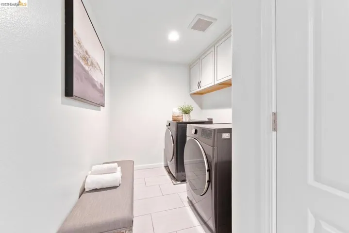 Laundry area featuring white cabinetry, a wood-finish shelf, and tile flooring