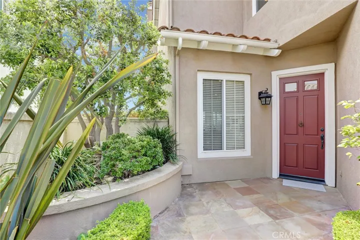 A welcoming covered entry with stone flooring, mature landscaping, and a private front porch creates an inviting first impression before stepping inside the home.