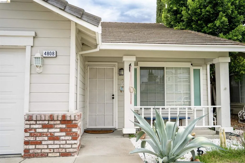 Inviting front facade featuring horizontal siding and a red brick accent wall