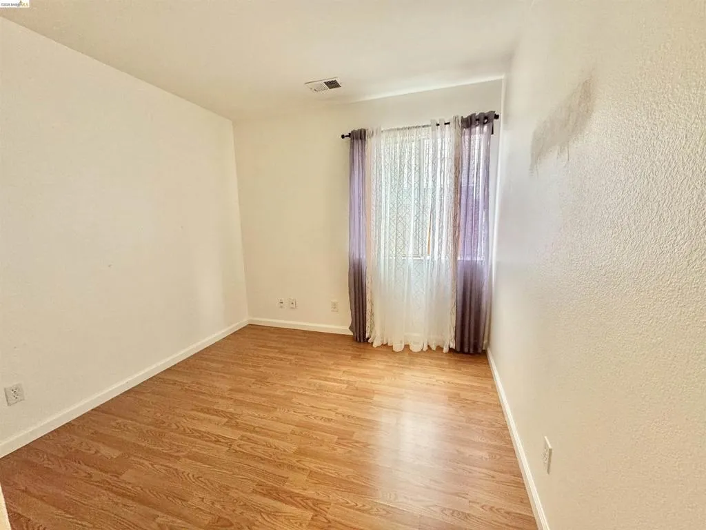 Room featuring wood-finish flooring, white baseboards, and textured walls