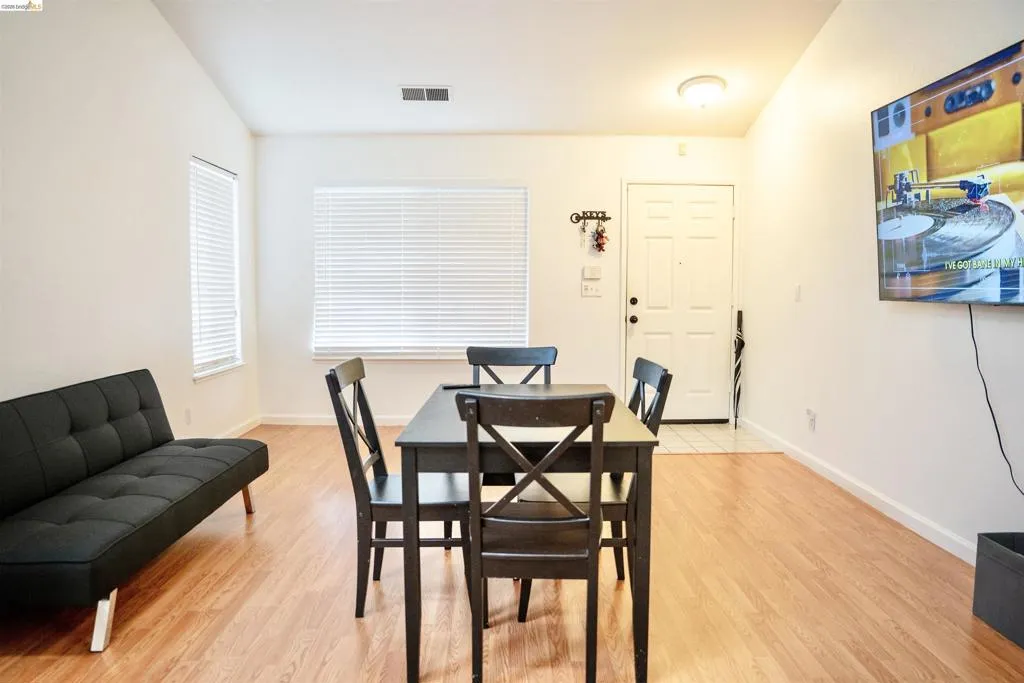 Open-concept living area featuring wood-finish flooring, white walls, and vaulted ceilings