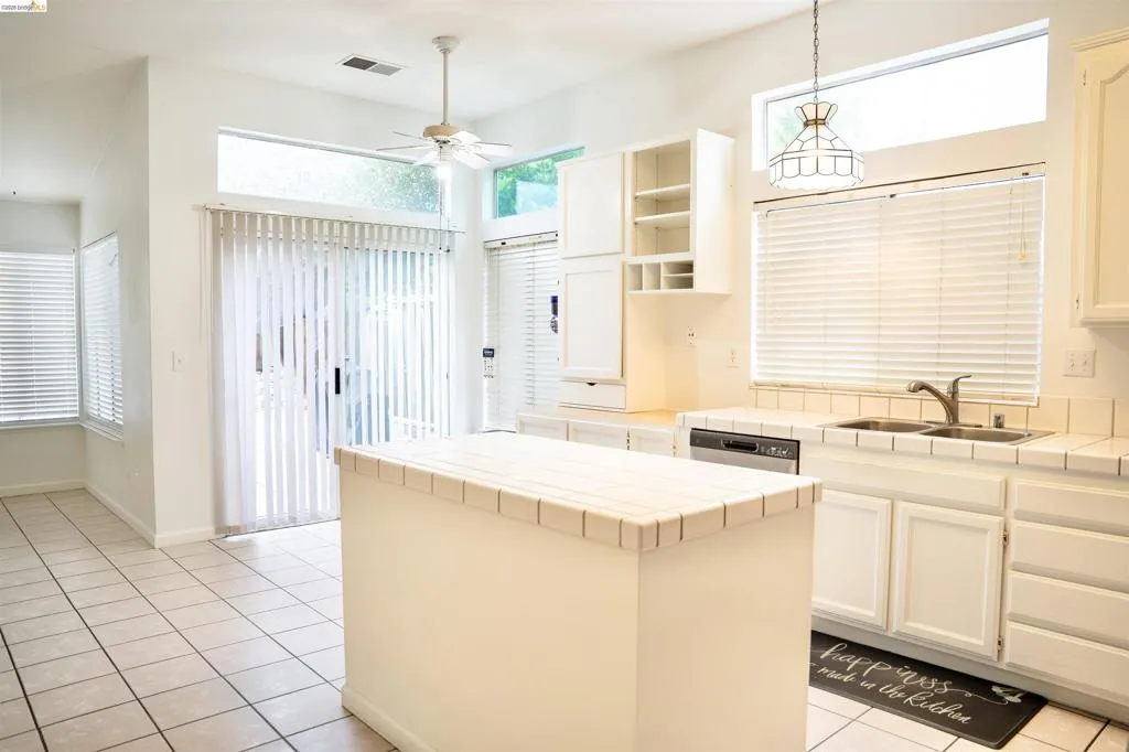 White tile flooring throughout, featuring a central kitchen island with tile countertop