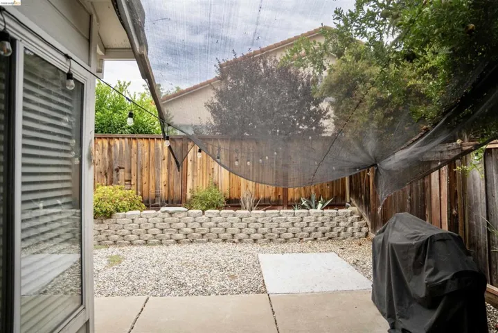 Patio area featuring concrete pavers, gravel ground cover, and a retaining wall