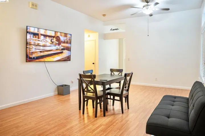 Open-concept living area with wood-finish flooring, vaulted ceilings, and a ceiling fan