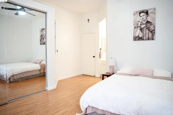 Bedroom featuring wood-finish flooring, a full-height mirrored closet, and a ceiling fan with integrated lighting