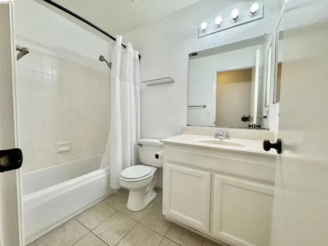 Bathroom featuring a white vanity with integrated sink, chrome faucet, and a large mirror with overhead lighting