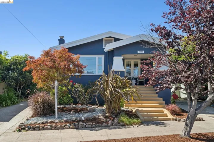 Exterior featuring a deep blue facade with white trim, a covered porch entry, multi-pane front door, and a prominent front-facing window