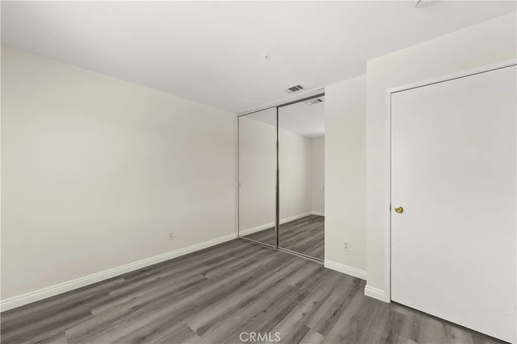 Guest room with new paint, new flooring, and mirrored closet doors.