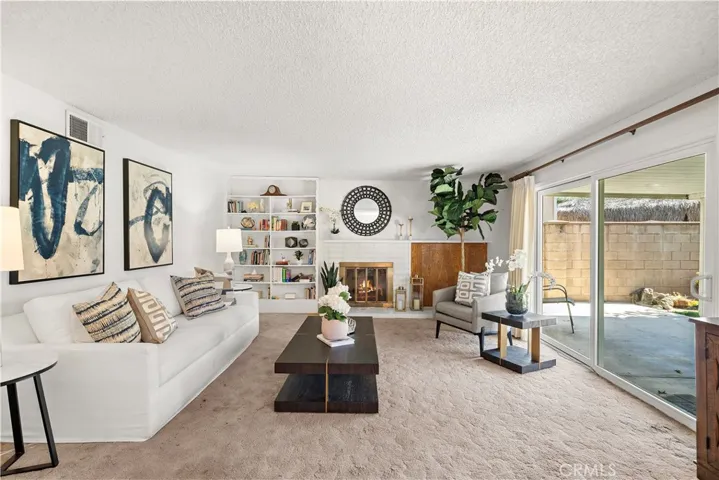 Living Room with Fireplace, Built-In Shelving, and Sliding Glass Doors Opening to Backyard
