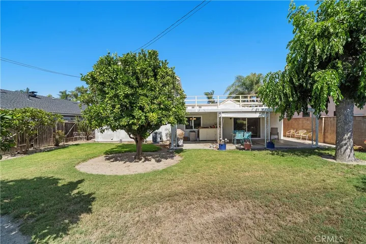 Park-like backyard is a tranquil oasis with an expansive covered patio, sprawling lawn, manicured gardens, lush foliage, ornamental trees, beautiful lily of the Nile, and an abundance of fruit trees, including lemon, orange, grapefruit, mandarin orange, and Bartlett pear.
