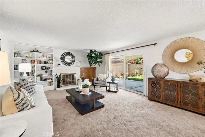 Living Room with Fireplace, Built-In Shelving, and Sliders Opening to the Backyard Covered Patio