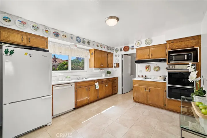 Light and Bright Kitchen with Eat-In Space for Breakfast Table, Tile Countertops, Natural Wood Cabinetry, and Walk-In Pantry