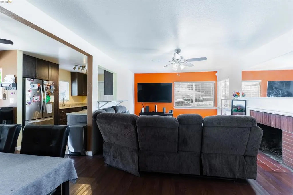 Open-concept living area featuring rich wood-finish flooring and an exposed brick fireplace