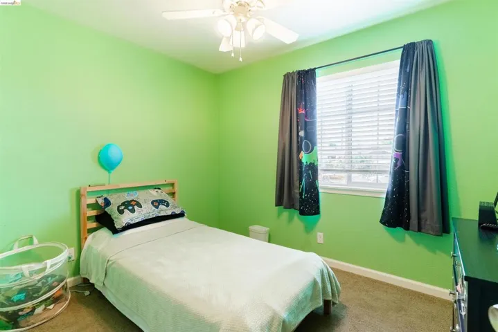 Room featuring a ceiling fan, a window with blinds, and light-colored carpeting