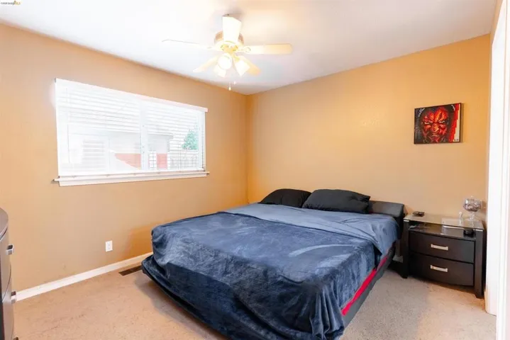 Bedroom featuring a ceiling fan, carpet flooring, and a window with blinds
