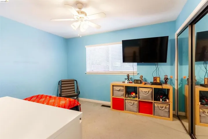 Room featuring light blue walls, a ceiling fan with integrated lighting, and a window with blinds