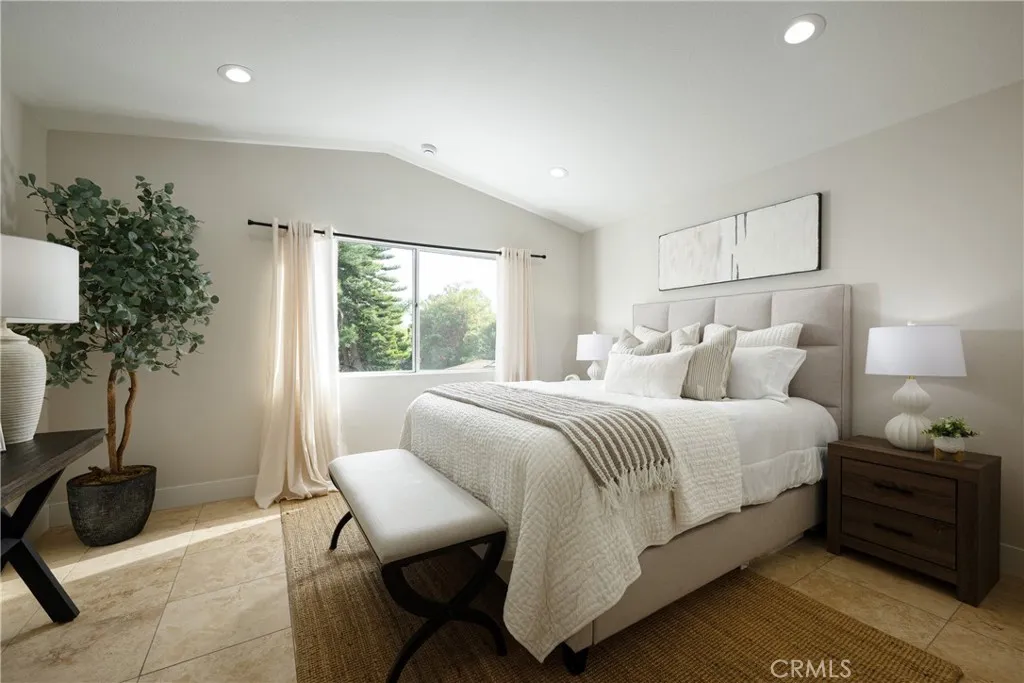The stunning primary suite located upstairs features a vaulted ceiling, recessed lighting and travertine flooring.