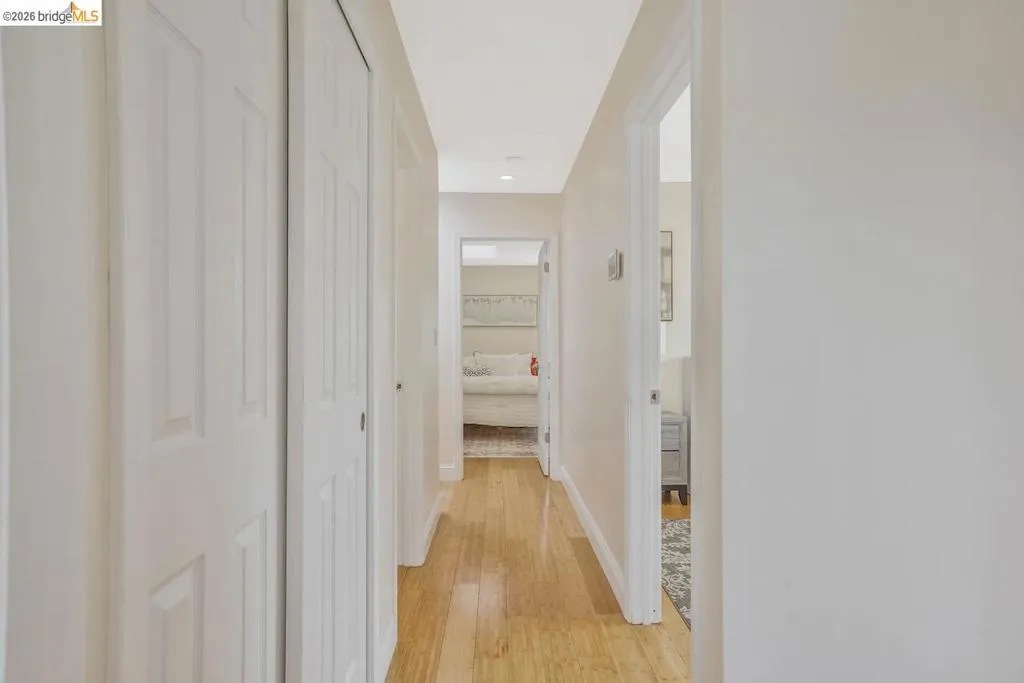 Hallway featuring wood-finish flooring, light-toned walls, recessed lighting, and multiple white panel doors