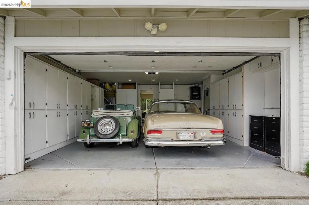 Two-car garage featuring extensive built-in cabinetry, overhead lighting, and a concrete floor