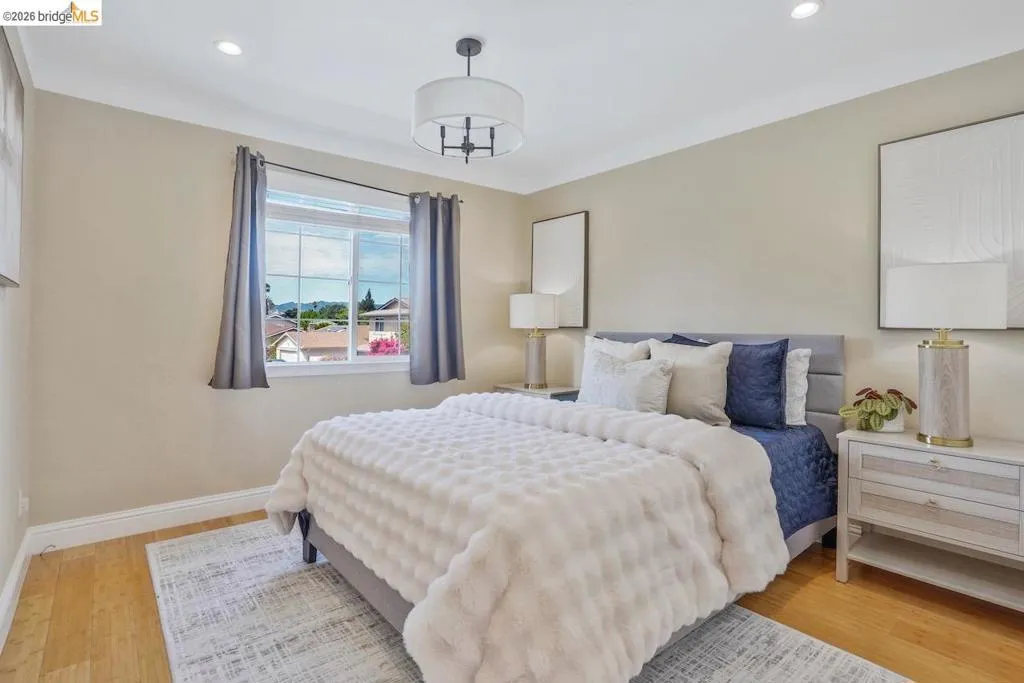 Bedroom featuring light wood-finish flooring, a window with exterior views, and recessed ceiling lighting