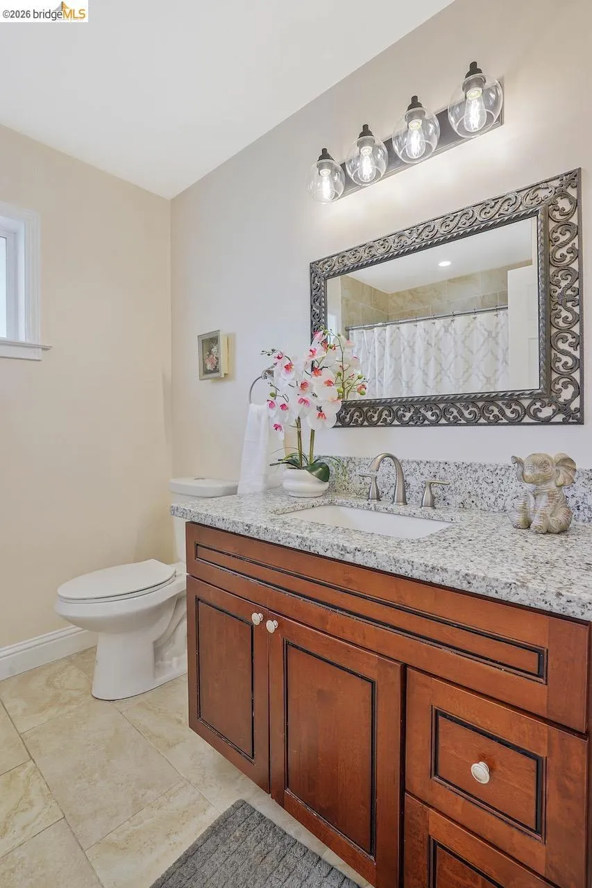 Bathroom vanity featuring a granite-style countertop, undermount sink, and wood-finish cabinetry
