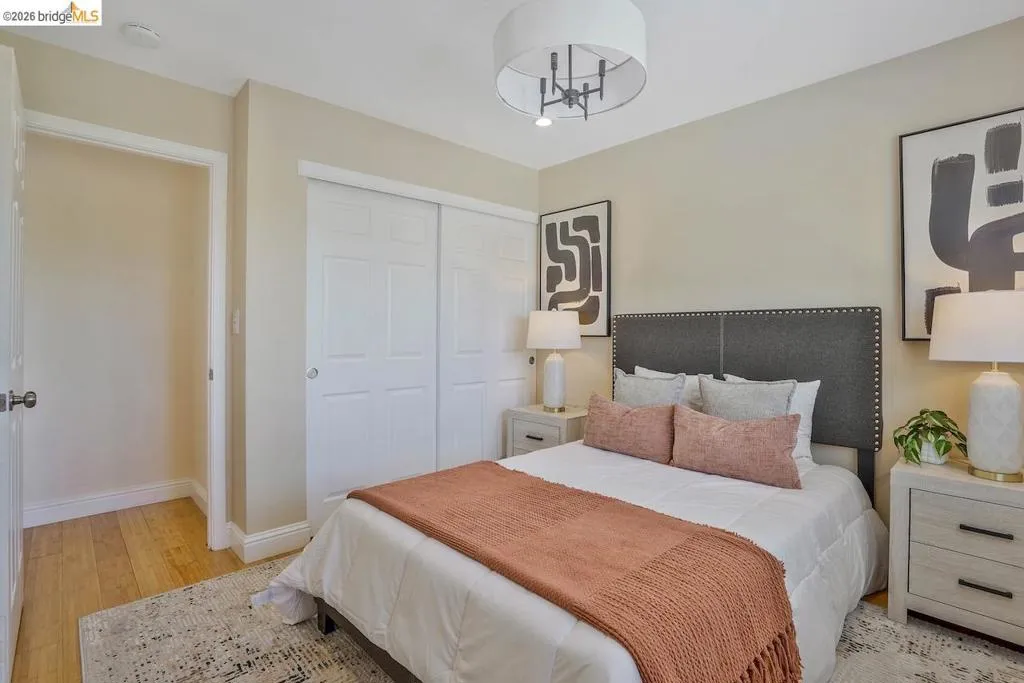 Bedroom featuring warm-toned walls, wood-finish flooring, a contemporary drum chandelier, and double sliding closet doors