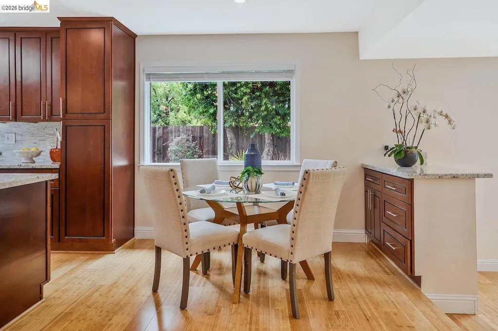 Kitchen featuring wood-finish flooring, a light-colored tile backsplash, dark wood cabinetry, and light-toned countertops