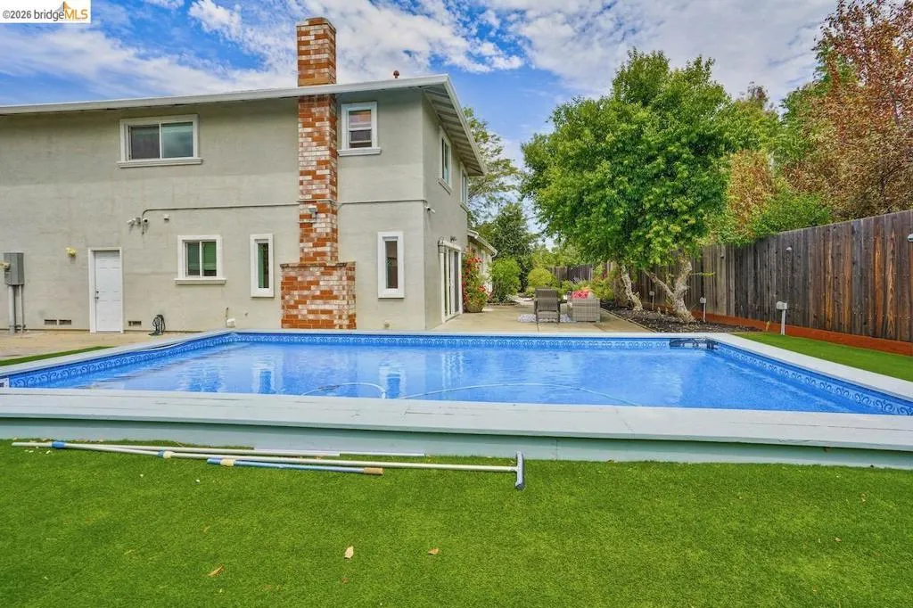 Expansive backyard featuring a rectangular swimming pool with a light blue liner and surrounding white coping