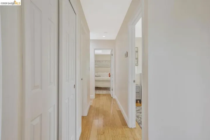 Hallway featuring wood-finish flooring, light-toned walls, recessed lighting, and multiple white panel doors