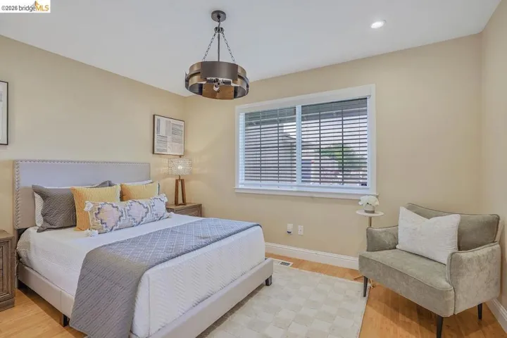 Bedroom featuring a modern chandelier, light wood-finish flooring, recessed lighting, a window with horizontal blinds, and neutral wall tones