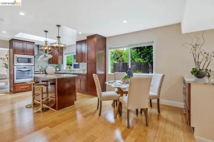 Kitchen with wood-finish flooring, dark wood cabinetry, light-toned countertops, and built-in stainless steel appliances
