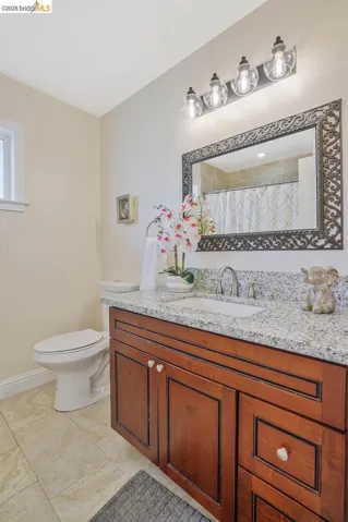 Bathroom vanity featuring a granite-style countertop, undermount sink, and wood-finish cabinetry