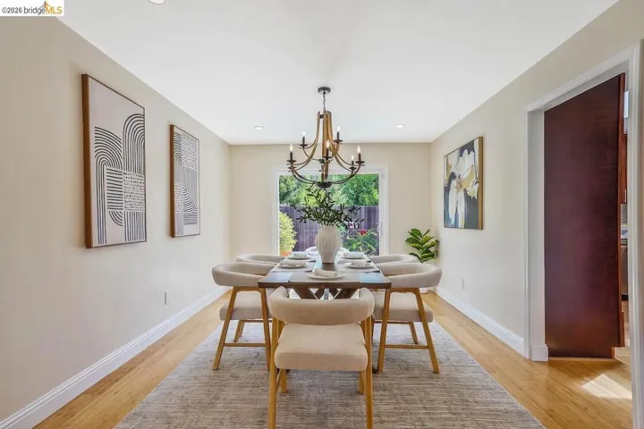 Hardwood-style flooring throughout this dining area, featuring recessed lighting and a multi-arm chandelier