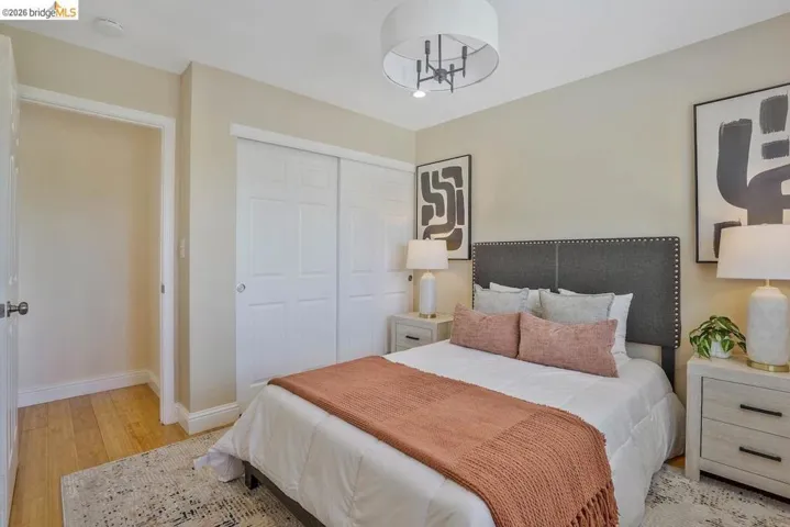 Bedroom featuring warm-toned walls, wood-finish flooring, a contemporary drum chandelier, and double sliding closet doors