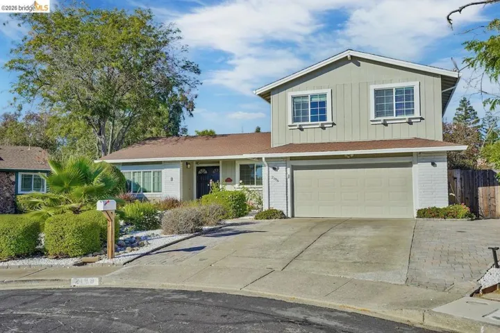 Multi-level residence featuring a two-car garage, light-colored siding, and a contrasting brown roof
